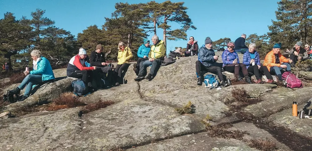 En turgruppe som spiser matpakkene sine på tur.