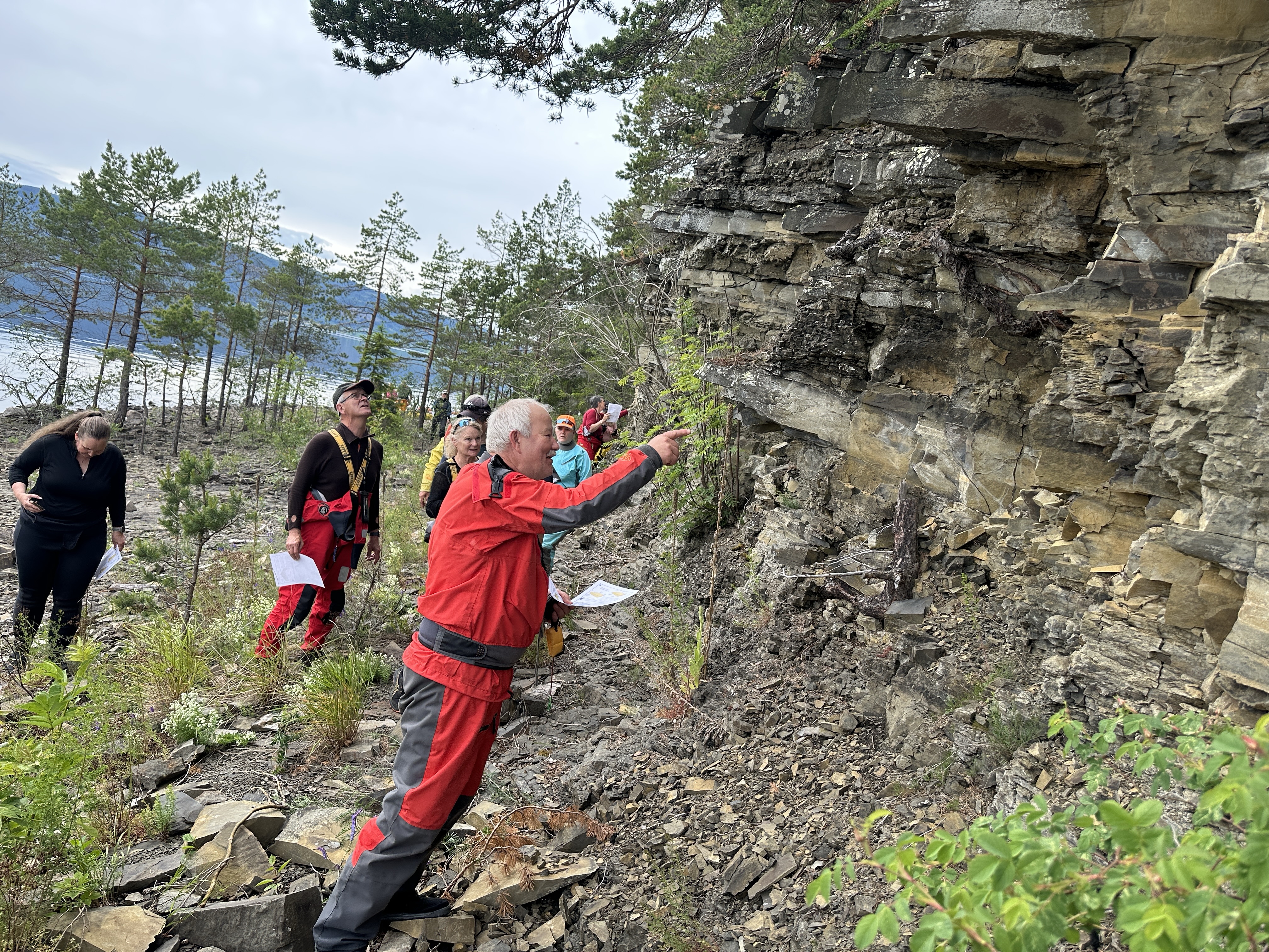 Bildet viser padlere i t&oslash;rrdrakter som g&aring;r langs fjellskr&aring;ningen og sjekker bergarter.