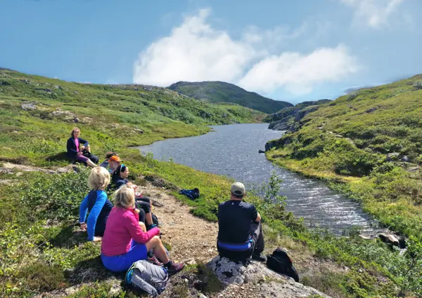 Turfølget ser på utsikt over fjell og vann