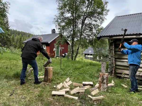 To mennesker som står å hugger ved