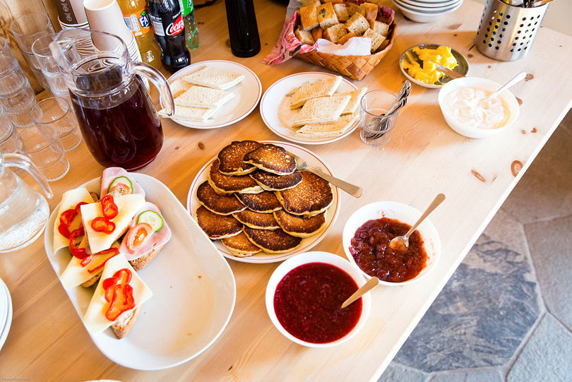 Lapper, smørbrød og syltetøy som er dekket opp på et bord.