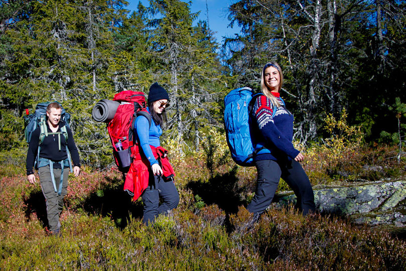 Tre glade folk på tur i skog