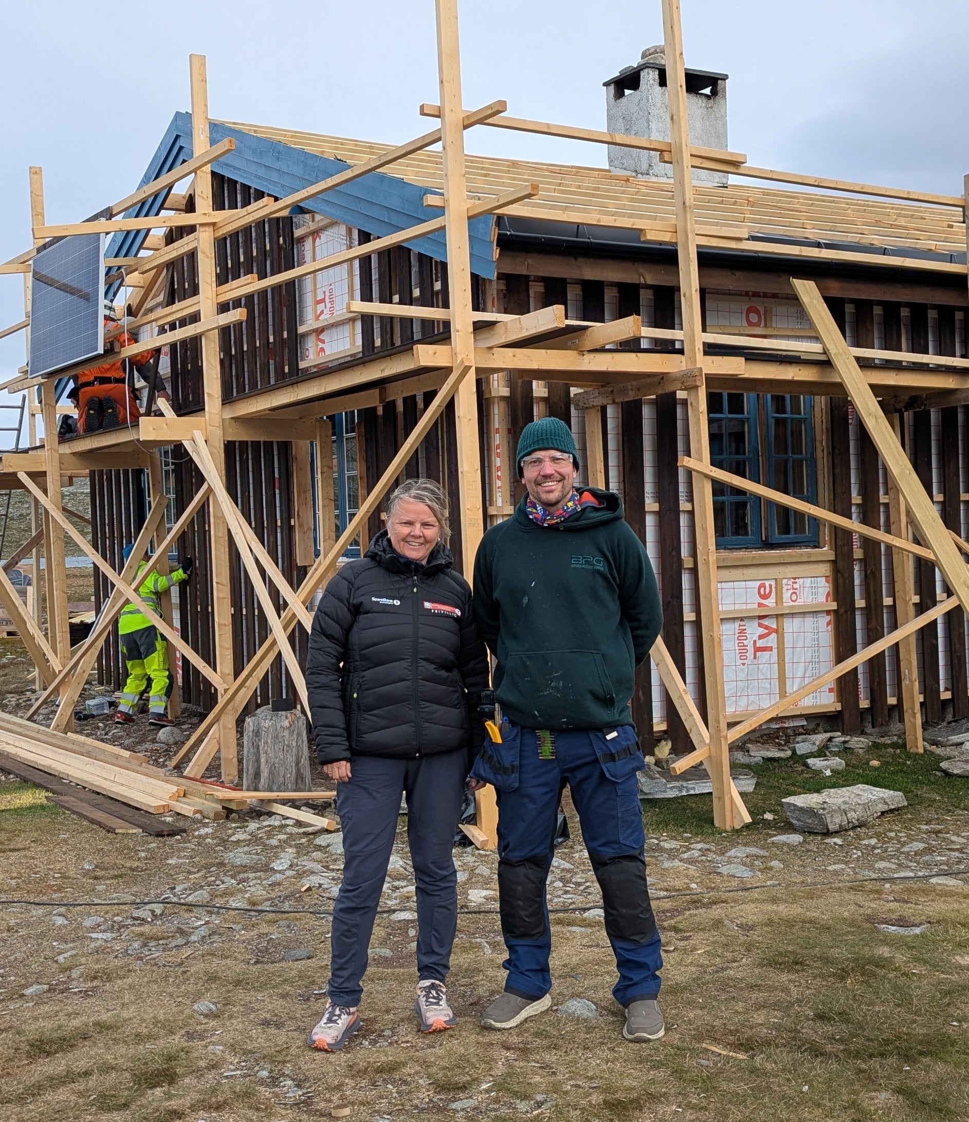 2 personer poserer foran hytte under arbeid