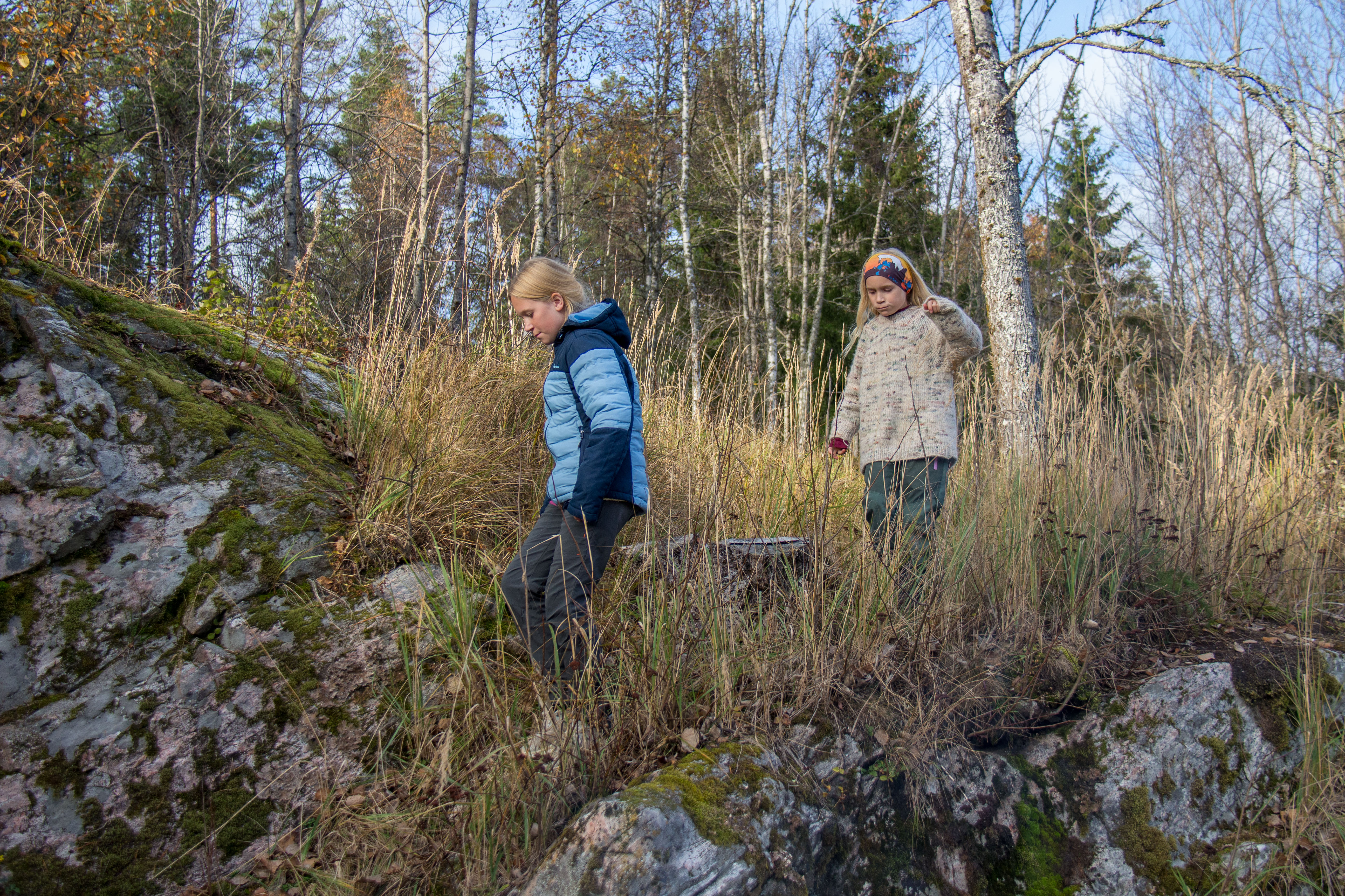 To jenter går i høyt gress.