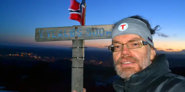 Selvportrett av mann på fjelltopp i solnedgang