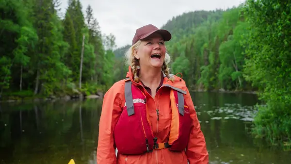 Dame med rød jakke og caps på tur i skogen