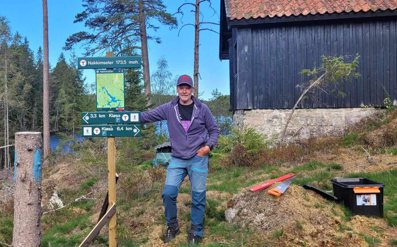 Mann har satt opp turskilter og står fornøyd ved siden