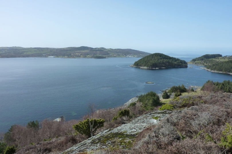 Utsikt fra topp mot sjø og vik.