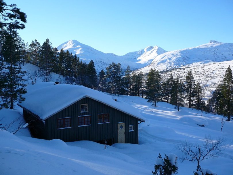 utsikt over hytta og videre mot fjellene i bakgrunnen