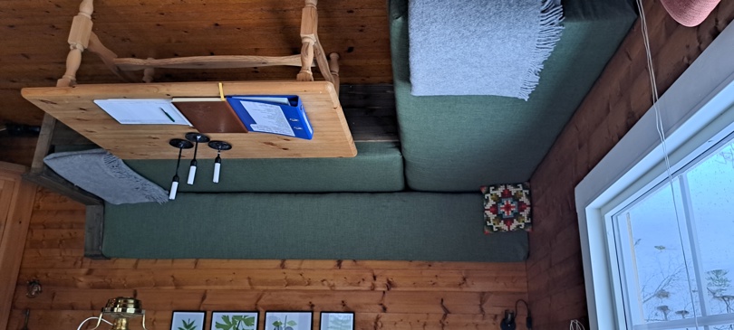 En grønn hjørnesofa i en hyttestue