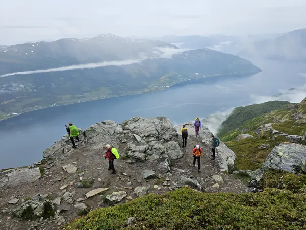 Mennesker står på fjell, i bakgrunn ser man fjord