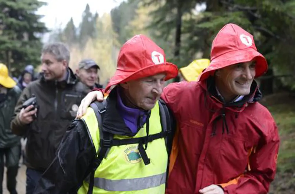 Jonas Gahr Støre og andre turgåare kledt i regnklede og sydvest med dnt-logo