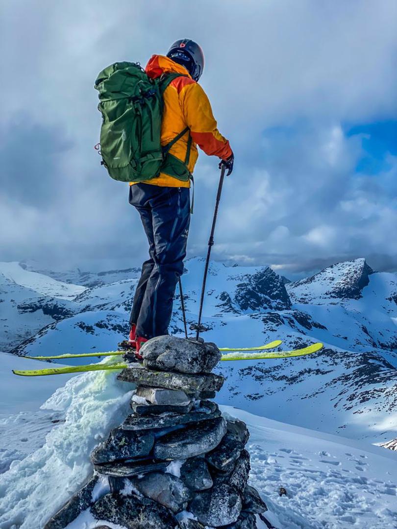 Toppturgåer på toppen av varden med ski på bena