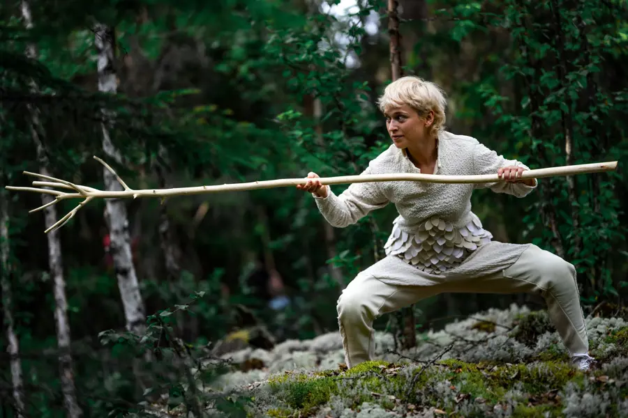 Danser i hvit drakt og lang kost i hånda
