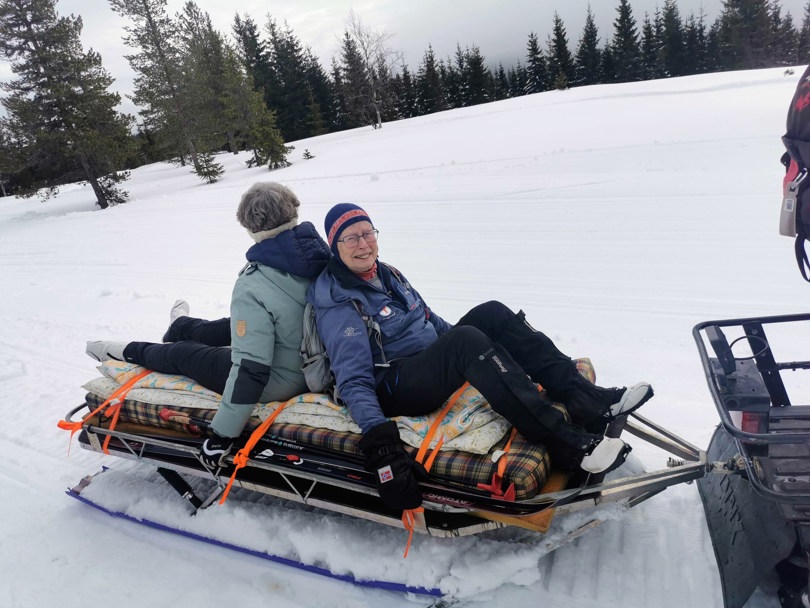 To personer sitter på snøscooter.