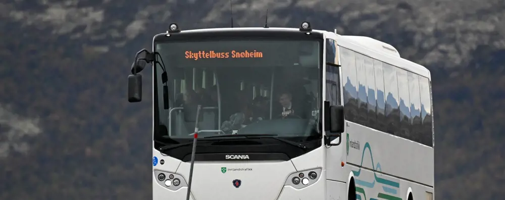 Hvit buss med tekst hvor det står Skyttelbuss Snøheim
