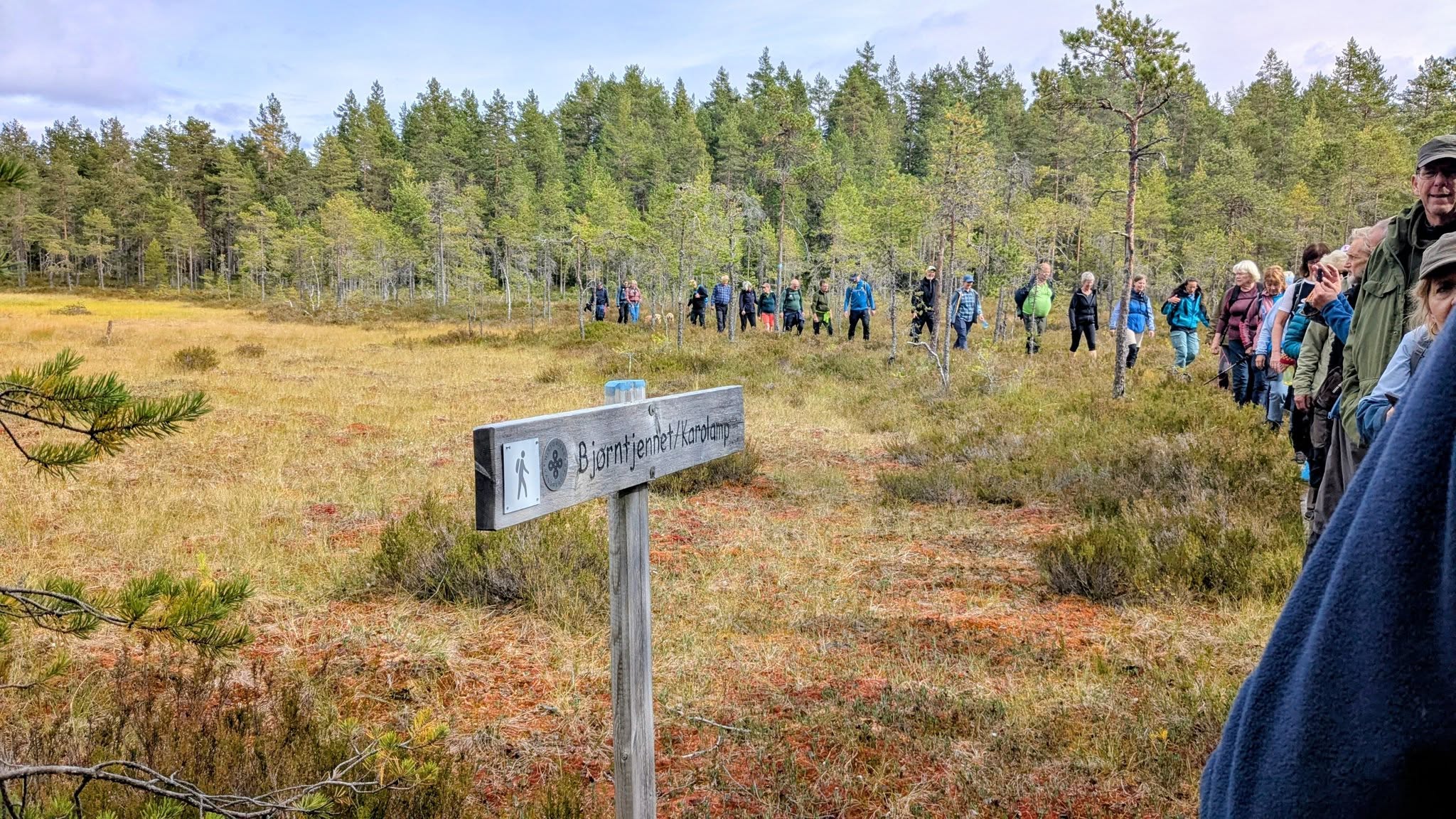 Turfølge på sti som går forbi skilt med både norsk og skogfinsk navn