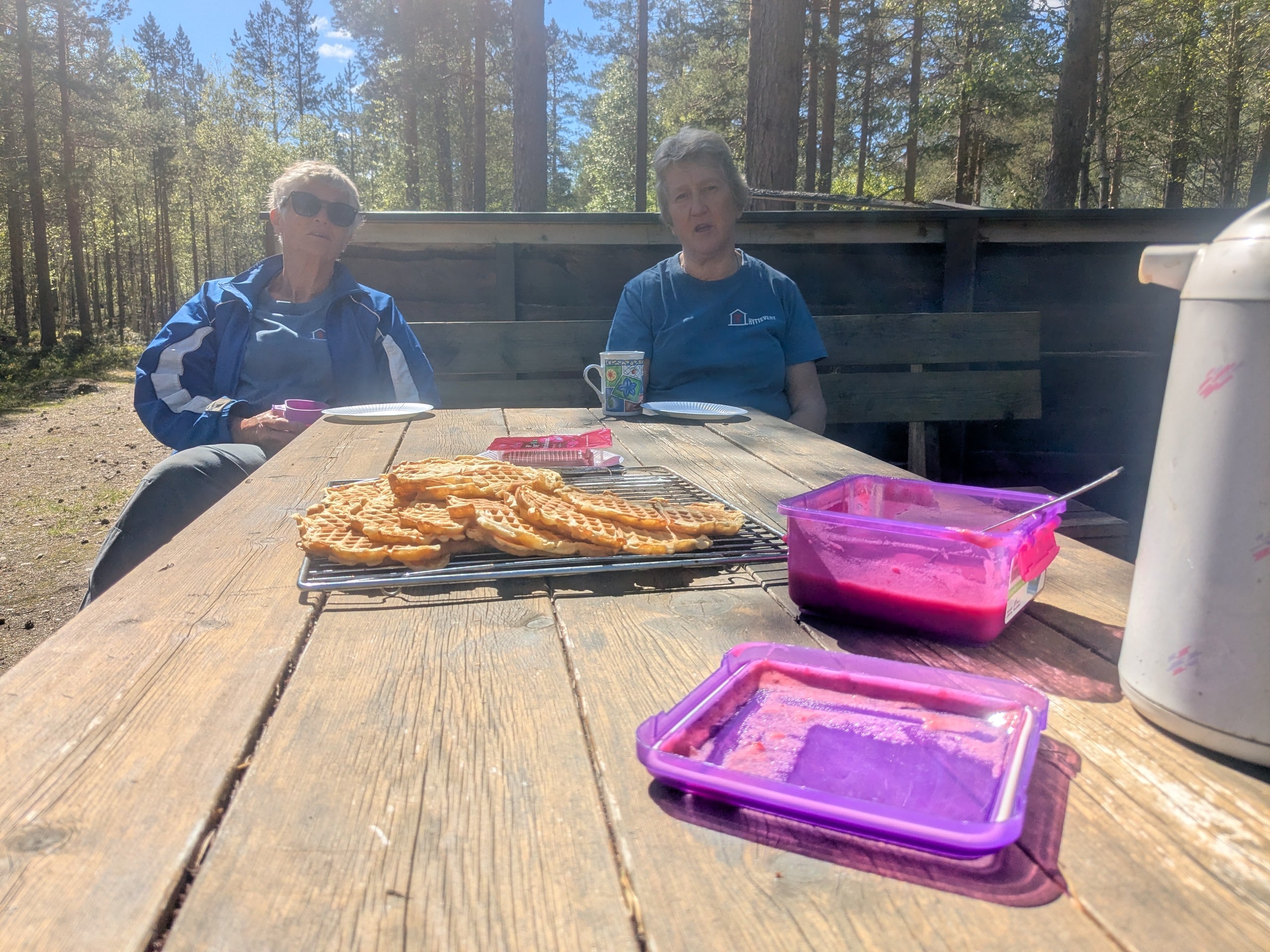 To damer som soler seg med vaffler p&aring; utebordet.