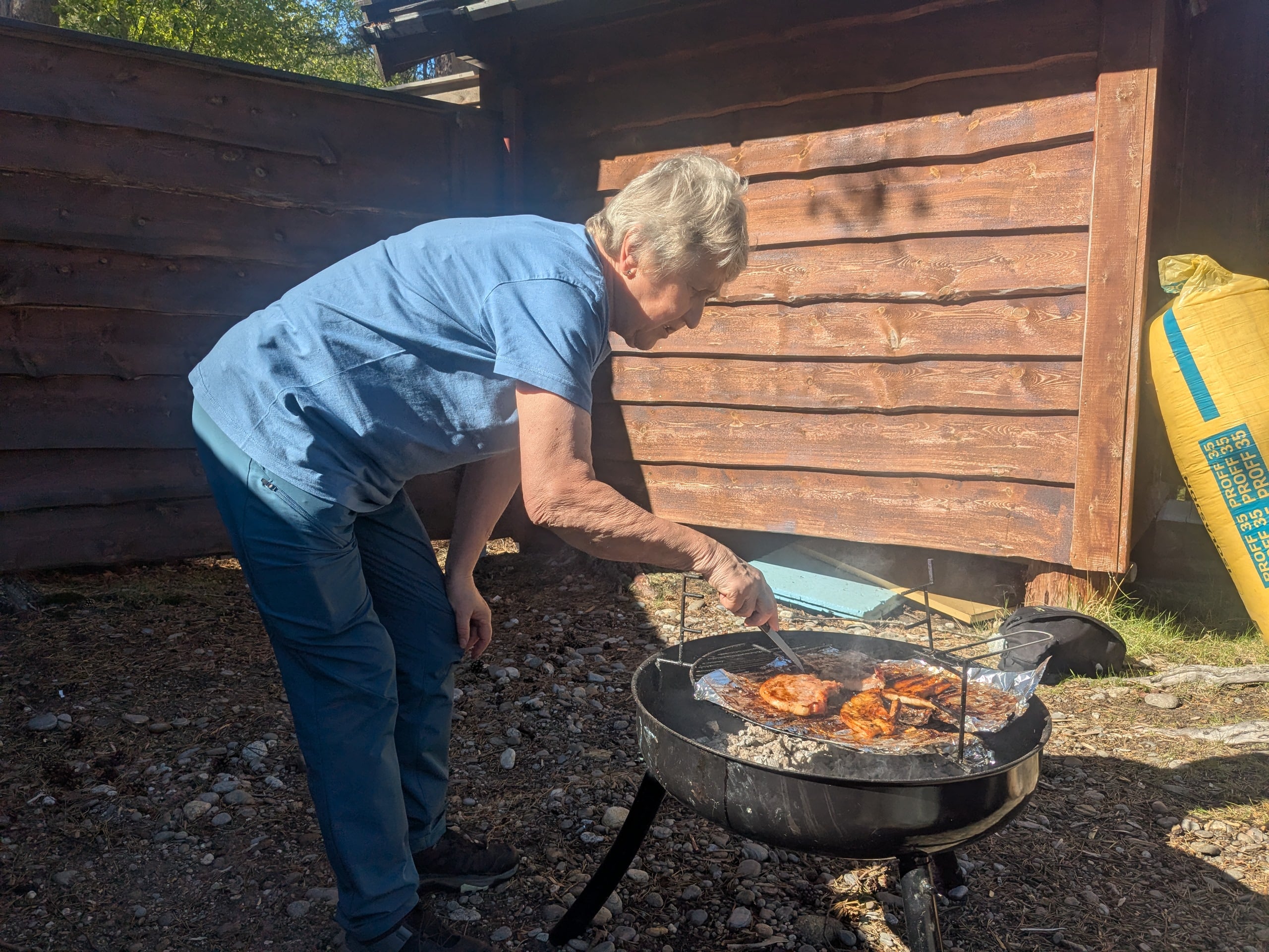 Dame som steker grillmat p&aring; en b&aring;lpanne utend&oslash;rs.