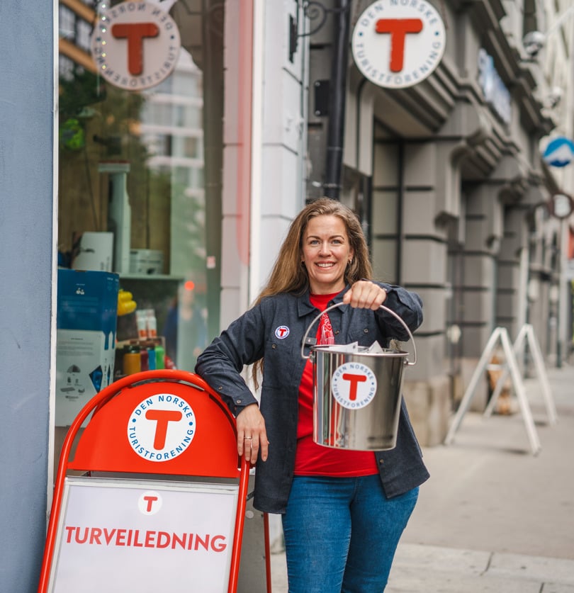 Person som står utenfor en butikk med en bøtte i den ene hånden
