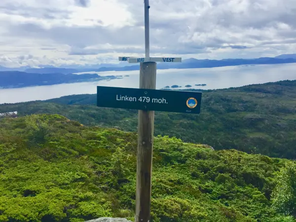 Eit dnt skilt merka Linken 479 moh i front med utsikt til fjord i bakgrunnen