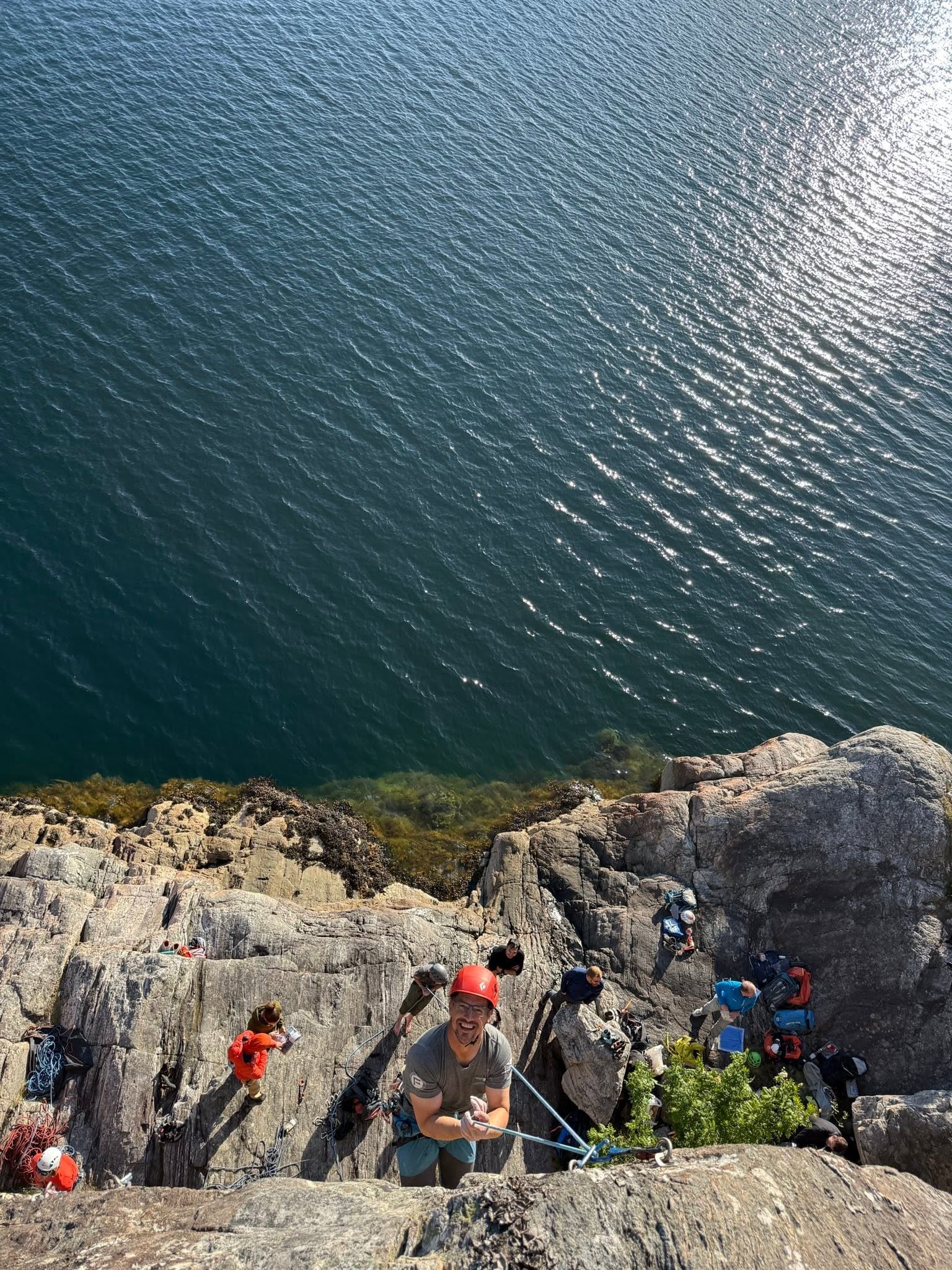 Mann klatrer i berg med sj&oslash; i bakgrunnen