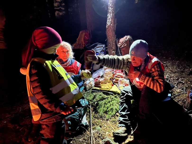 Et barn og to voksne sitter i skogen