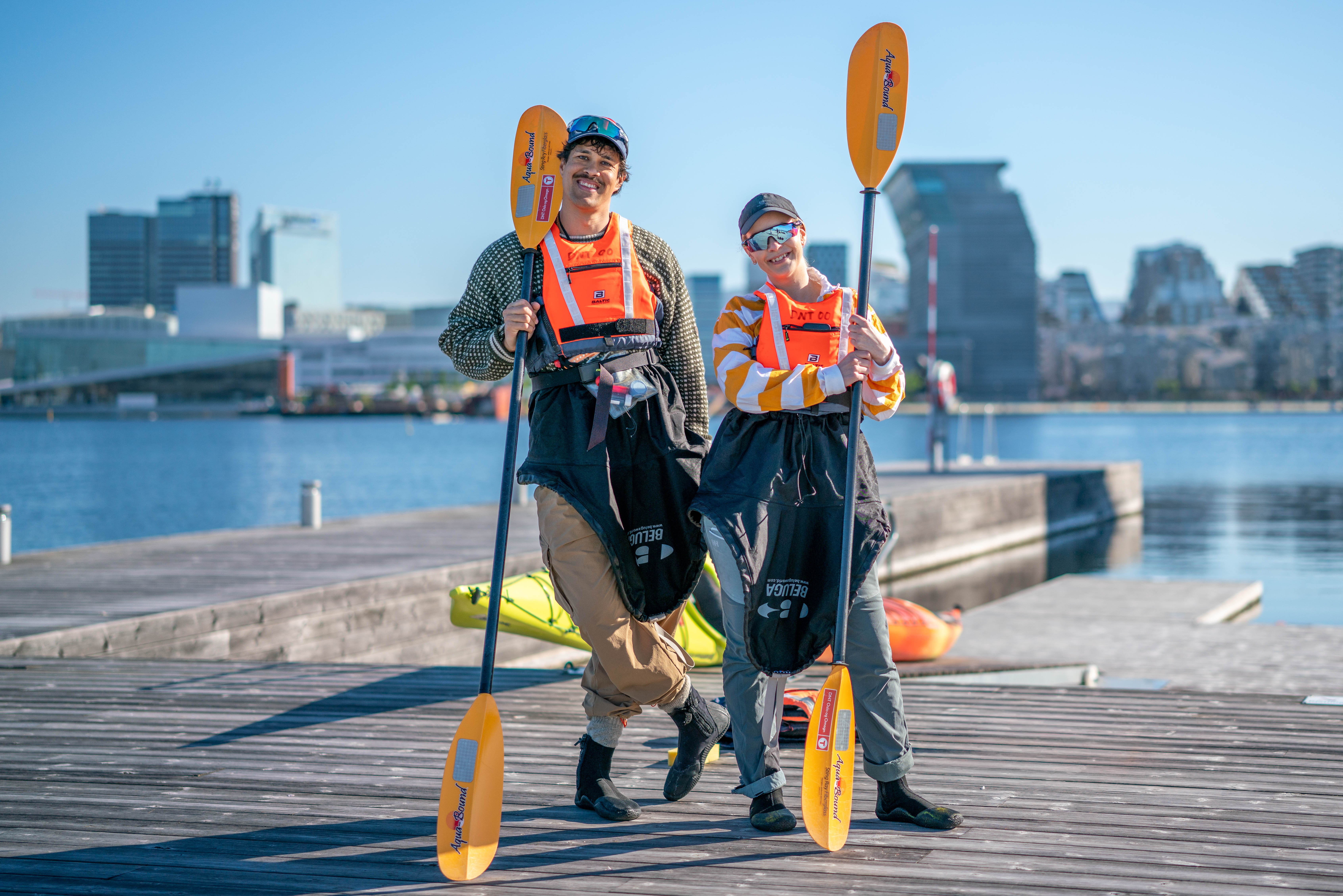 to personer i padleutstyr p&aring; en brygge med kajakk i bakgrunnen