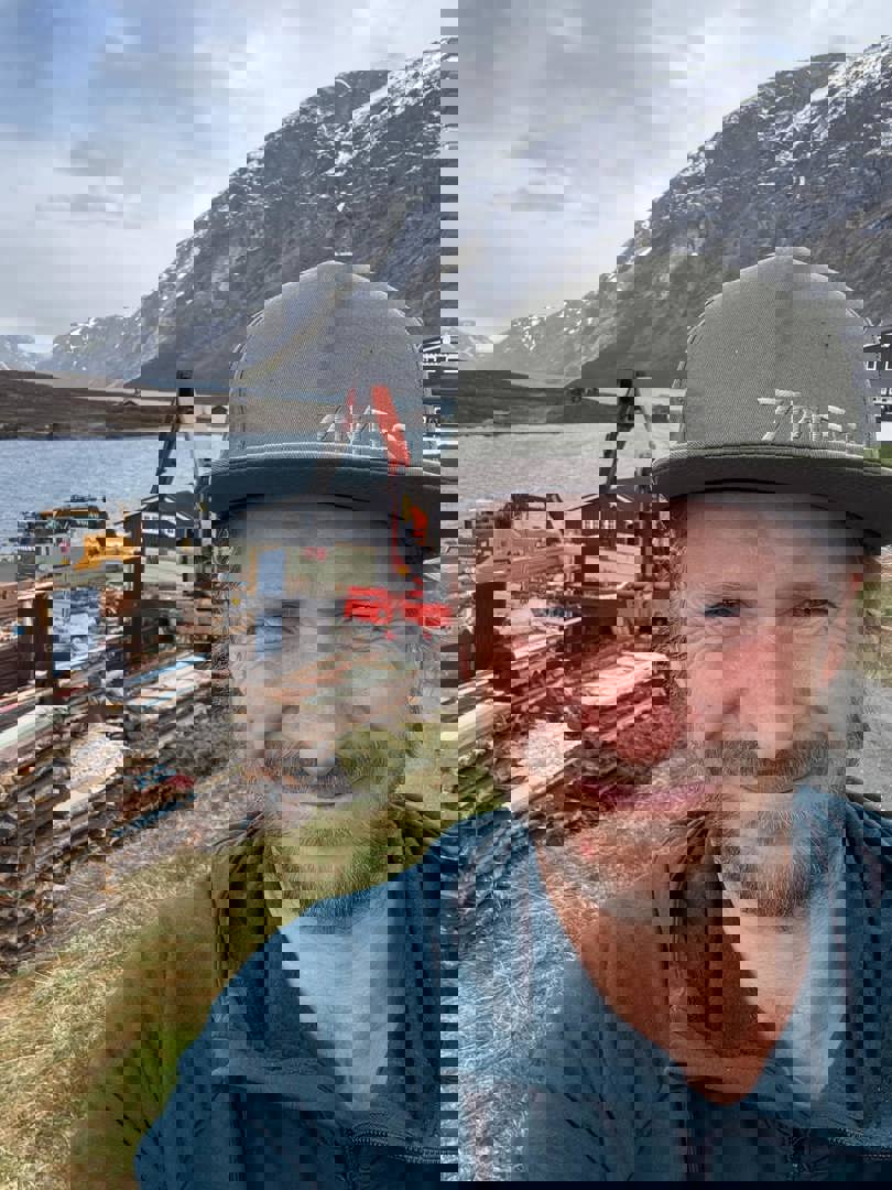 Mann med caps som står foran et revet bygg