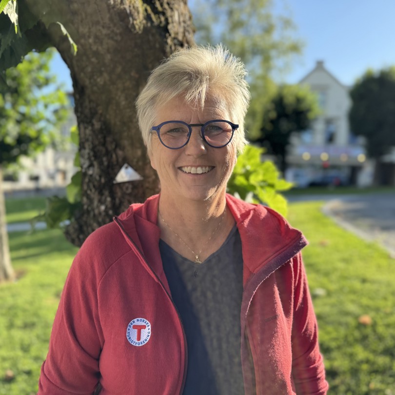 Bilde av en smilende dame foran et tre