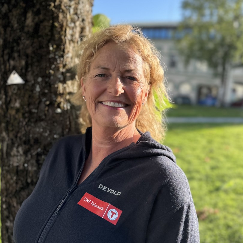 Smilende dame foran et tre