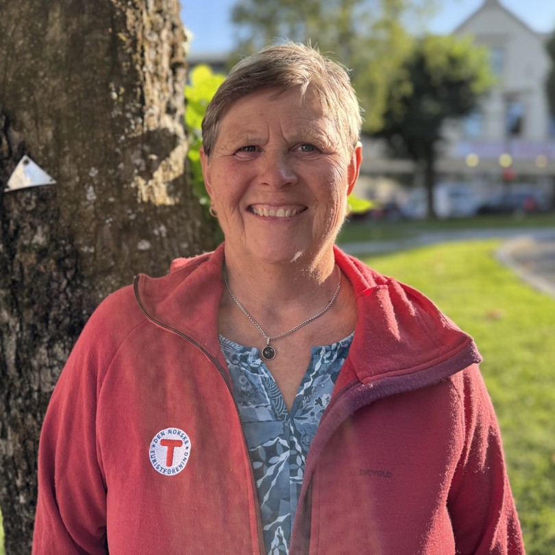 Bilde av en smilende dame foran et tre