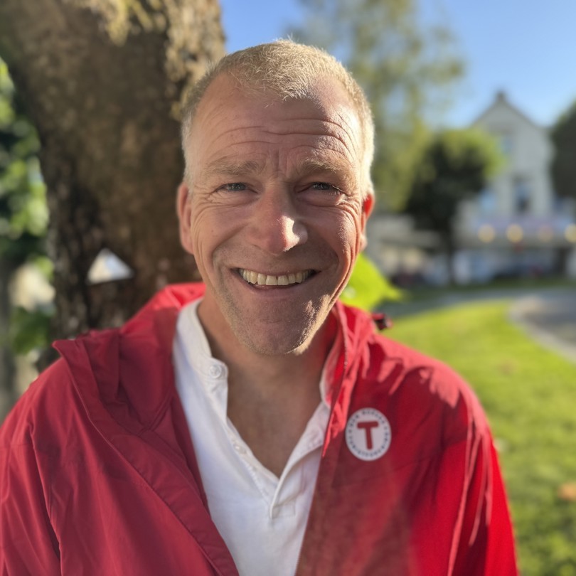 Bilde av en smilende mann foran et tre