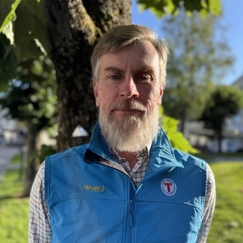 Bilde av en smilende mann foran et tre