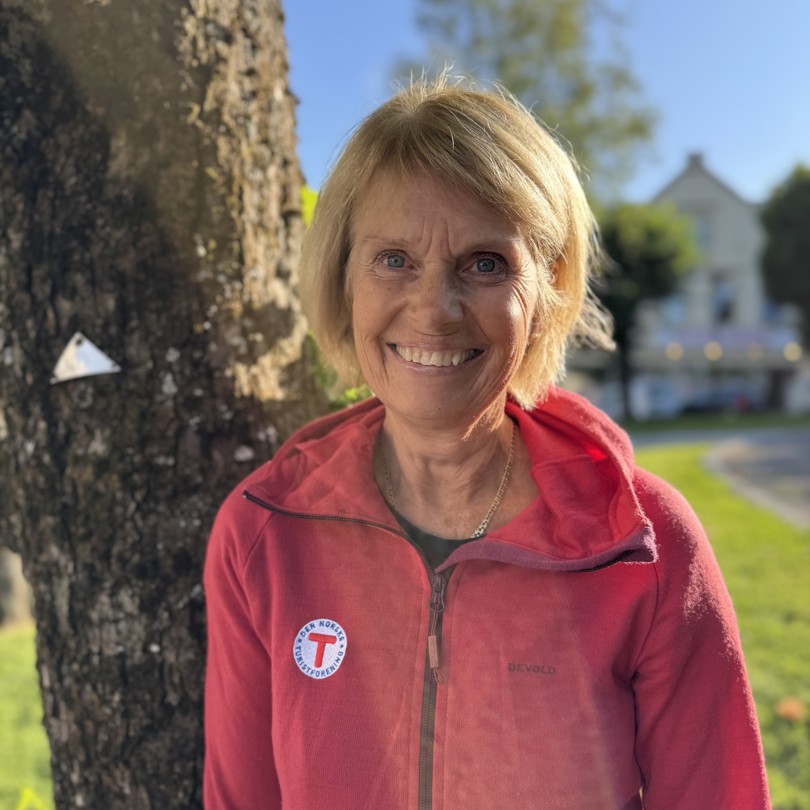 Bilde av en smilende dame foran et tre