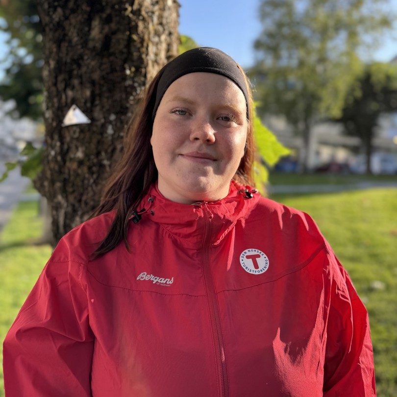 Bilde av en smilende dame foran et tre