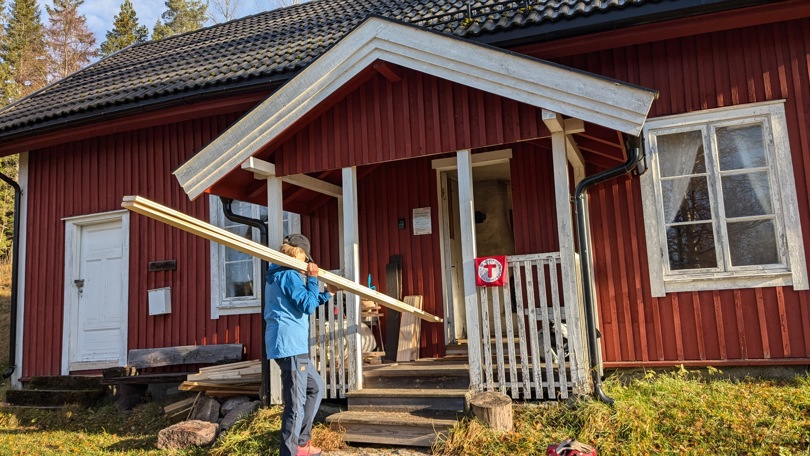 Styremedlem DNT Finnskogen og Omegn bærer inn gulplank til stuegulv Lebiko