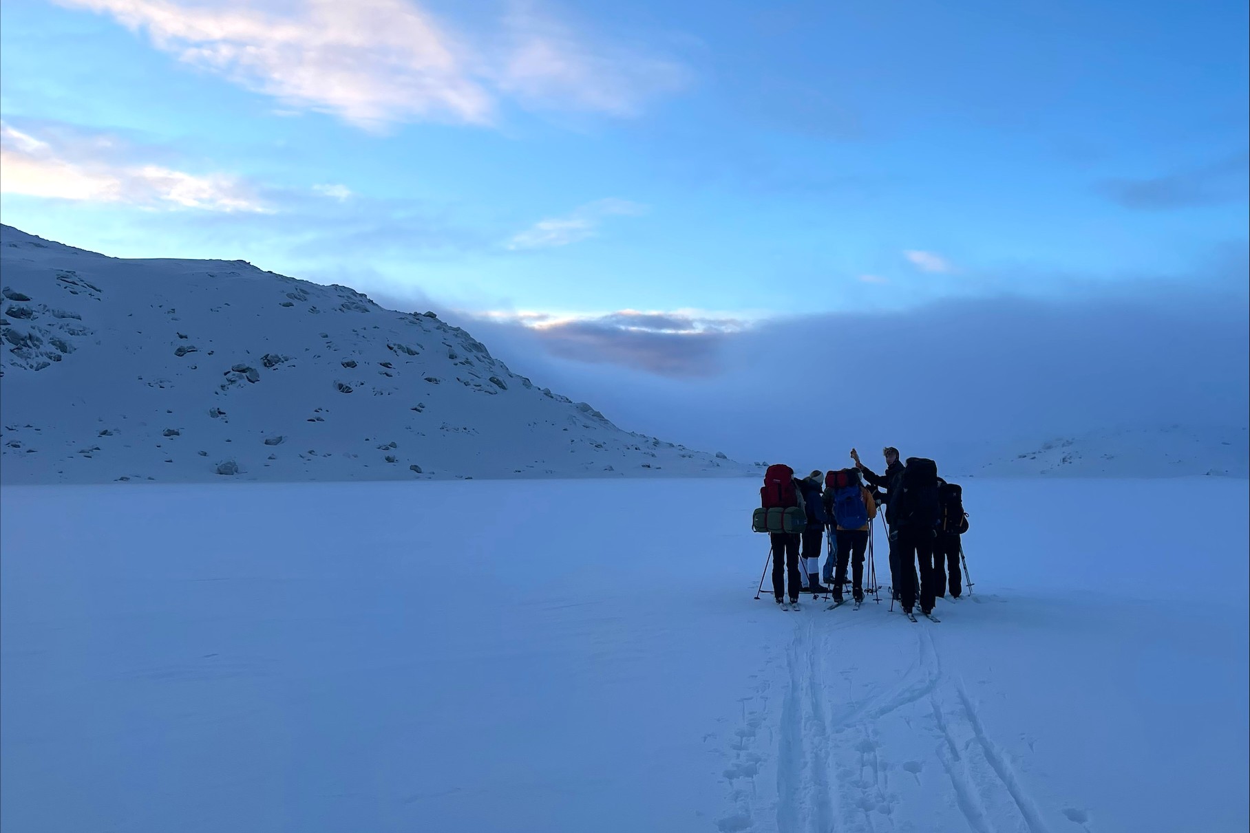 Gruppe skil&oslash;pere g&aring;r over sn&oslash;dekt landskap og setter skispor i sn&oslash;en