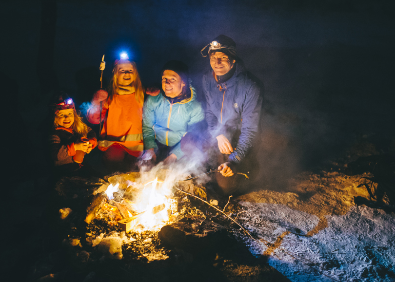 En familie som sitter rundt et bål