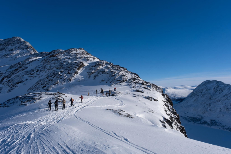 Flere personer som går over et fjell på vinterstid