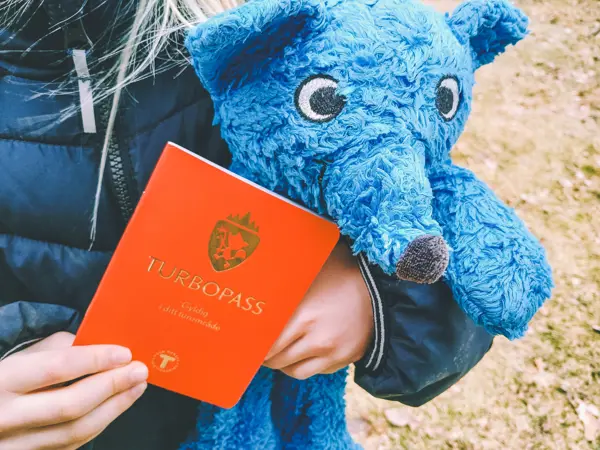 Et barn holder et rødt turbopass og en blå turbobamse