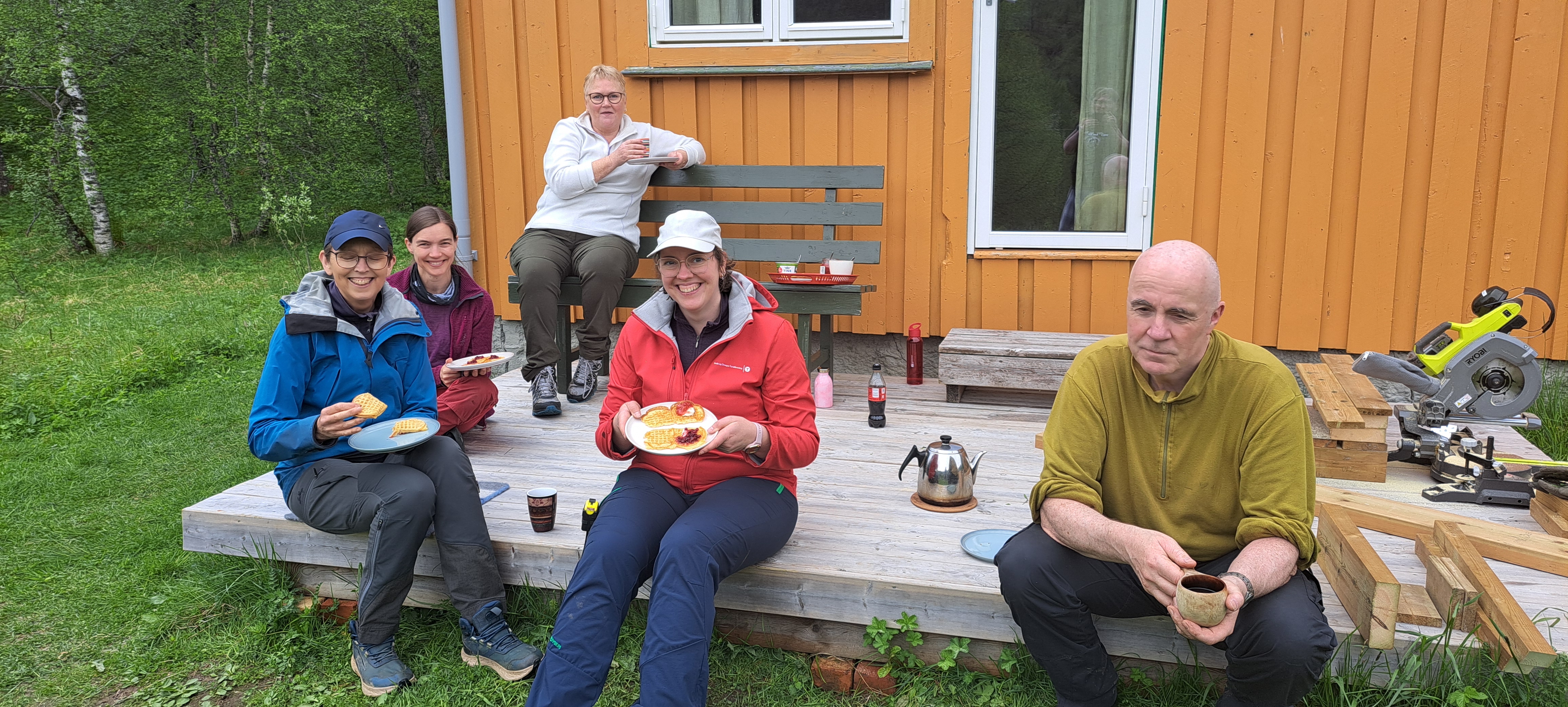 En munter gjeng spiser vaffler ute p&aring; en platt.
