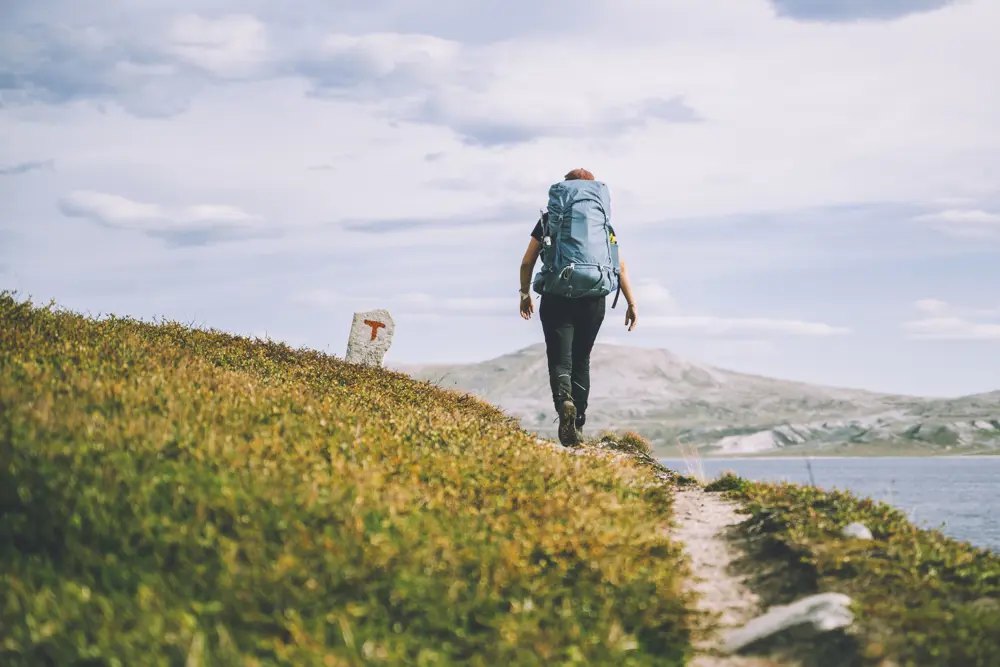 Person som går på tursti på fjellet, med utsikt