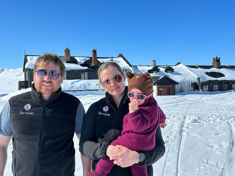 Bestyrere på Sandhaug, Svein Arne og Oda. Ute i strålende vinterføre, alle med solbriller og en liten jente på armen. 