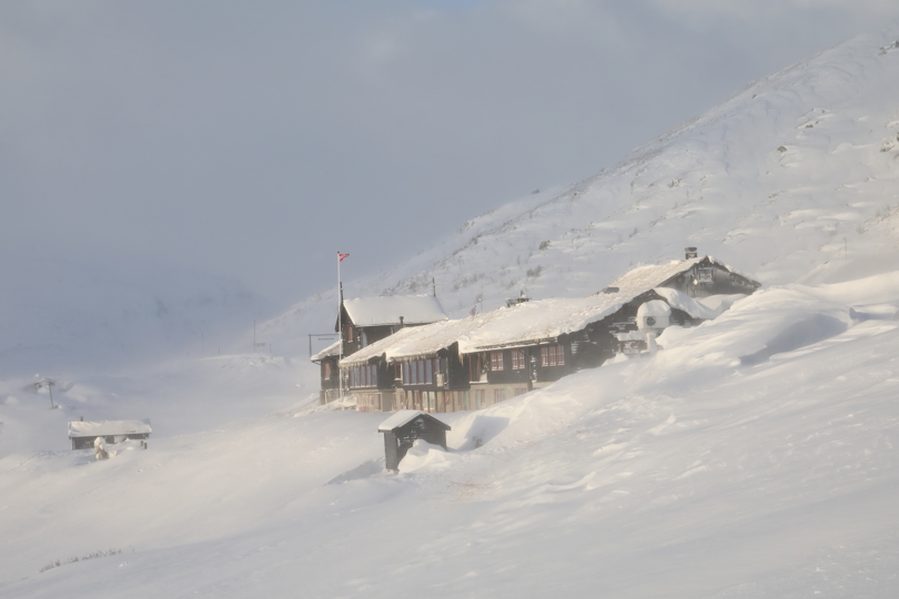 En nedfrosset fjellstue kledd i snø