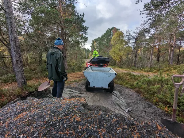 Mann skuffer grus opp i hengeren på en ATV
