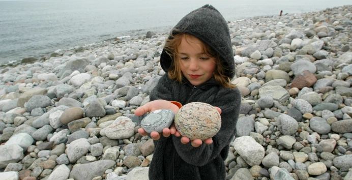 Jente holder steiner i fjæra