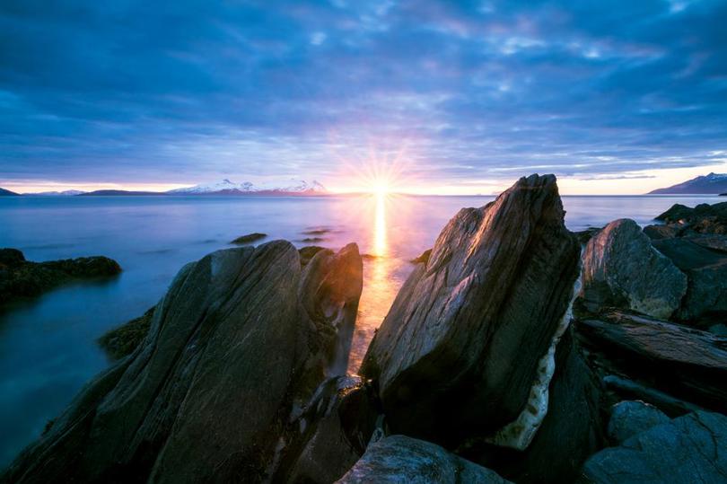 Steiner langs kysten i solnedgang.