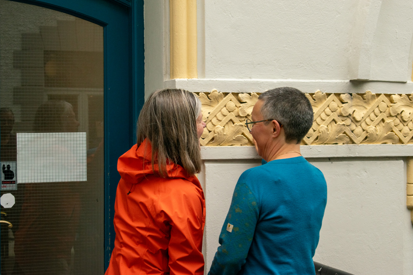 To personer ser på detaljer i muren på et jugendstilhus i Ålesund
