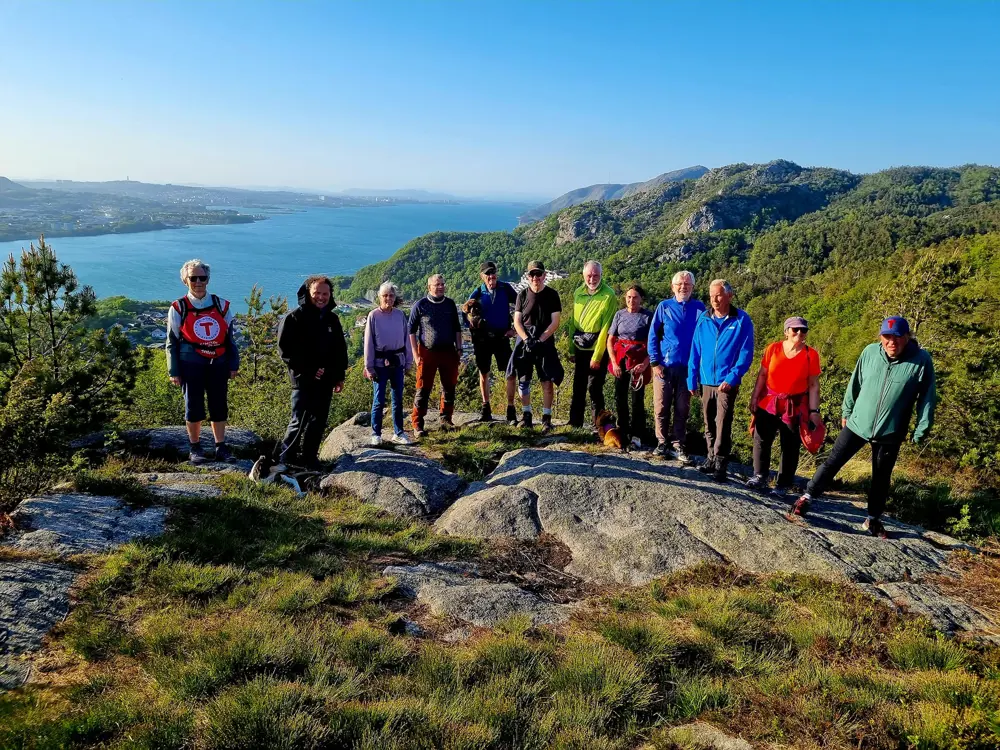 Voksne mennesker står samlet og smiler på et fjell